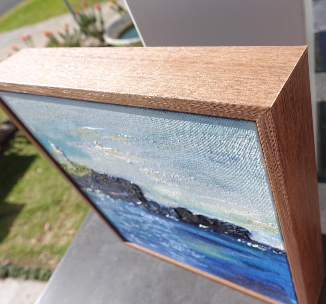 Kiama Lighthouse on a black rocky headland against a sapphire ocean and pastel sky. close up view.