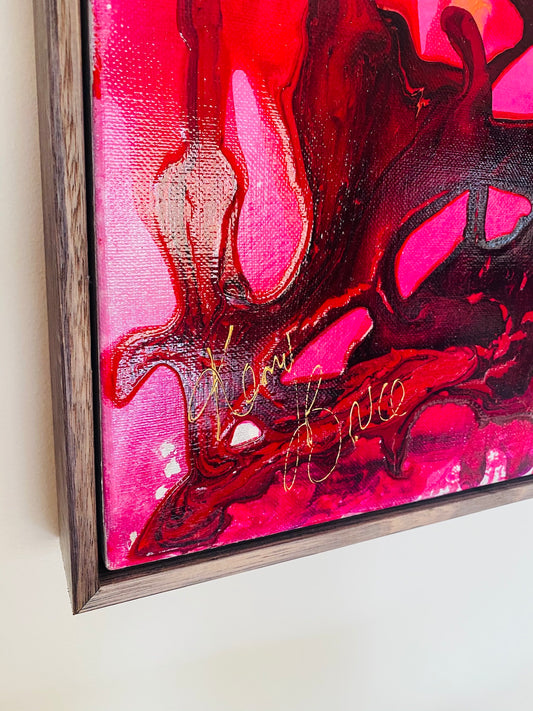 Varying shades of pink and red blooms in a black lace vase, framed in a charcoal oak box frame.