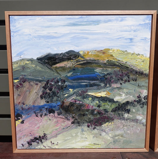 Abstract landscape with a countryside in colours of yellow, pink, green and blue. Framed view.