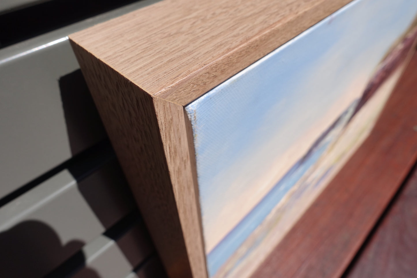 Ocean and rock pools in soft pastel colours with reddish brown cliffs. View of frame.