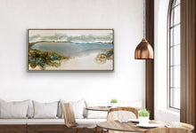 Load image into Gallery viewer, Ocean and beach scene with puffy clouds on the horizon and rocks in jewel like colours, painted in an abstract style. In situ on a white living room wall.
