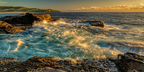 Waves breaking over rocks at Ourie Point on Werri Beach, Gerringong NSW.