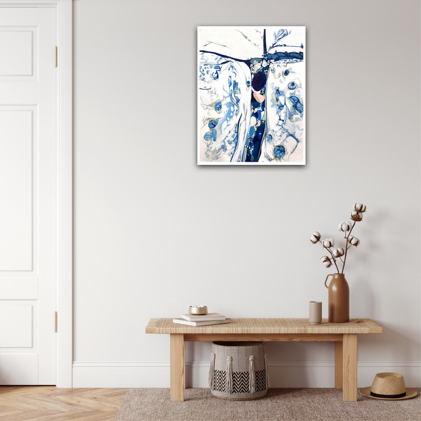 Abstract oil painting on a white background in shades of blue. Shown on a beige wall.