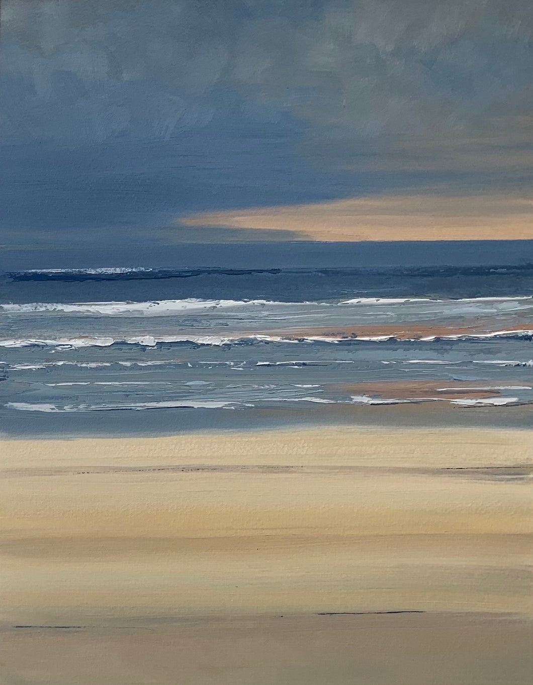 Beach on the NSW South Coast on a winter morning with a dark blue sky and a salmon pink streak in the clouds reflected on the ocean.