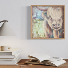 Load image into Gallery viewer, Highland cow standing in a pastel green field against a pastel blue sky. In situ on a wall above a shelf with books.

