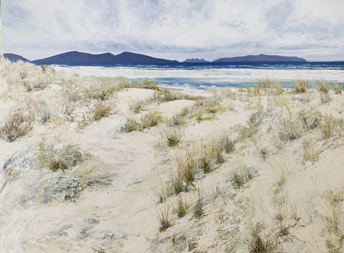 Tasmanian beach, deserted with windswept sand dunes, white sand, the ocean and mountains in the background.