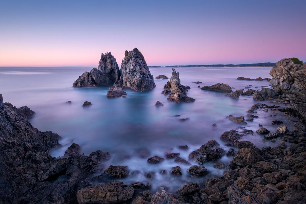 A photographic print of Camel Rock near Bermagui, on the NSW South Coast, against a pink and purple sky.
