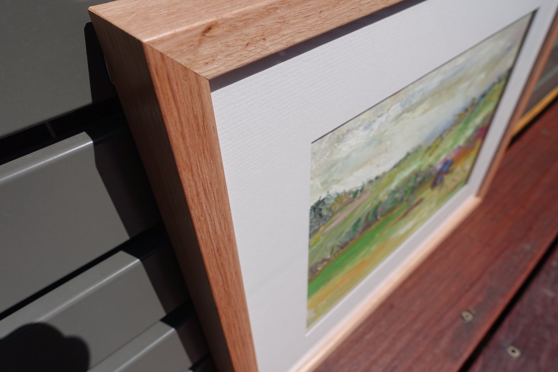 Abstract painting of a green countryside with a blue tree in the foreground. Close up of Frame.