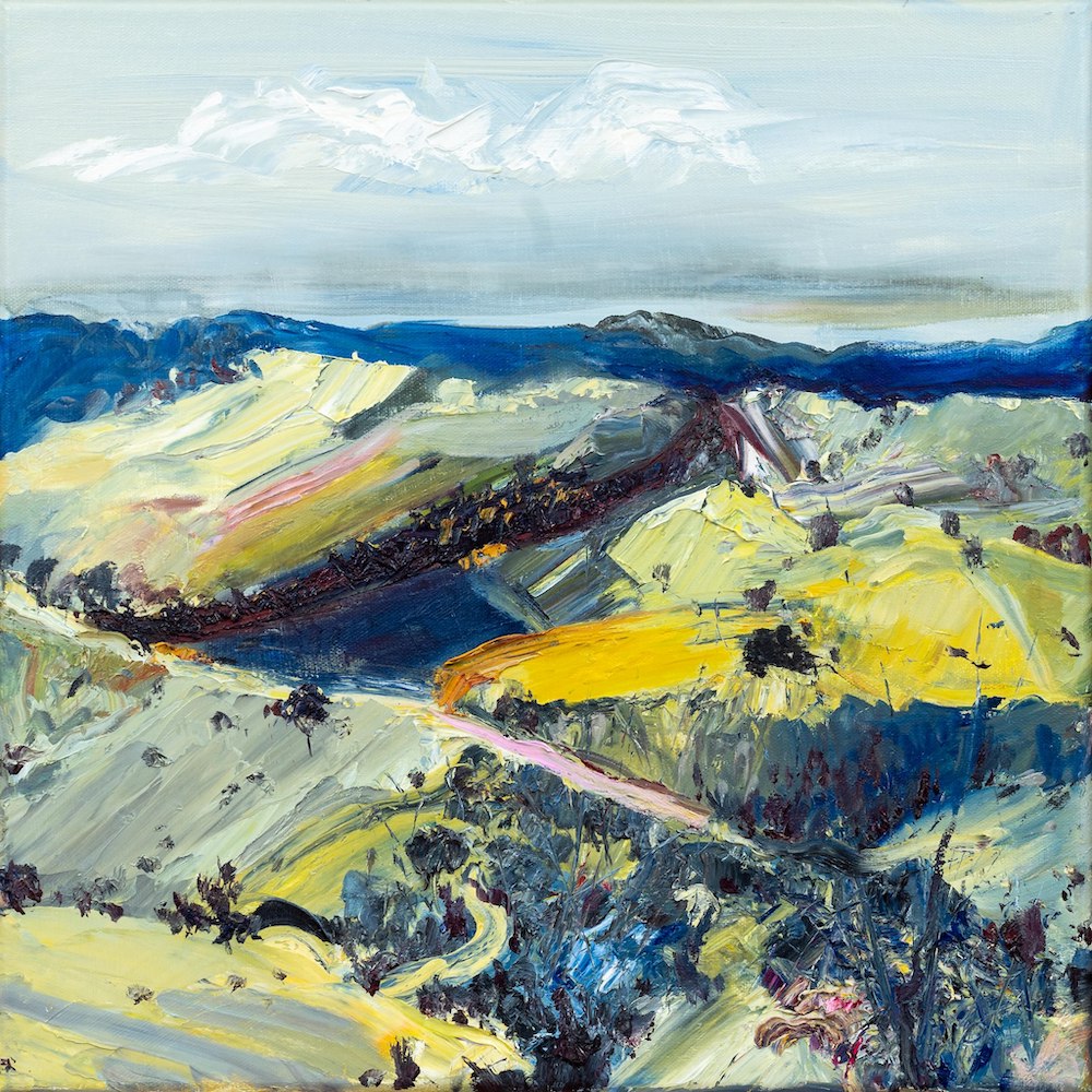Abstract oil painting of a country landscape with steep hills and lots of colour, yellow, pink, green and blue against a pale blue sky with white clouds.