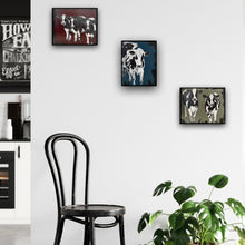 Load image into Gallery viewer, Two black and white cows standing side by side, gazing ahead, against an olive green and black background.  Shown in situ on a wall with two other paintings of cows.
