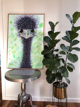Load image into Gallery viewer, An emu with green ringed eyes, against a green and white fleck background. Shown in situ against a white wall on a small round metal table.
