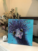 Load image into Gallery viewer, A fun, quirky colourful emu with purple feathers, gold rimmed eyes against an aqua background. Shown in situ on a white shelf.
