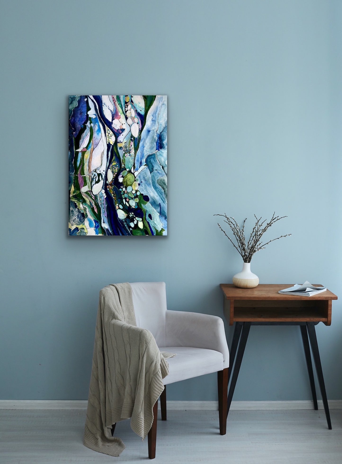 Contemporary abstract painting in shades of light blue, dark blue, turquoise, citrus, pink and white. Shown on a teal sitting room wall.