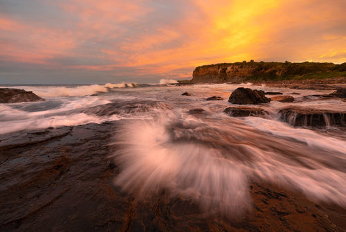 Sunset lights up the endless movement of 
water on the Kiama Coast Walk, Australia