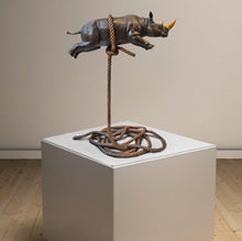 Load image into Gallery viewer, Bronze sculpture of a rhino with a gold horn, suspended on a bronze rope. Looking right.
