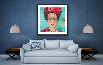 A beautiful and colourful limited edition print of Frida Kahlo with red and pink flowers in Frida's hair against a turquoise and aqua background, in a black frame on a blue wall.