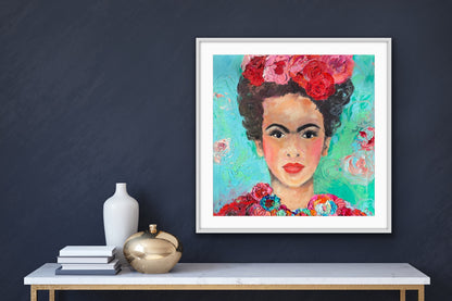 A beautiful and colourful limited edition print of Frida Kahlo with red and pink flowers in Frida's hair against a turquoise and aqua background, framed in white.