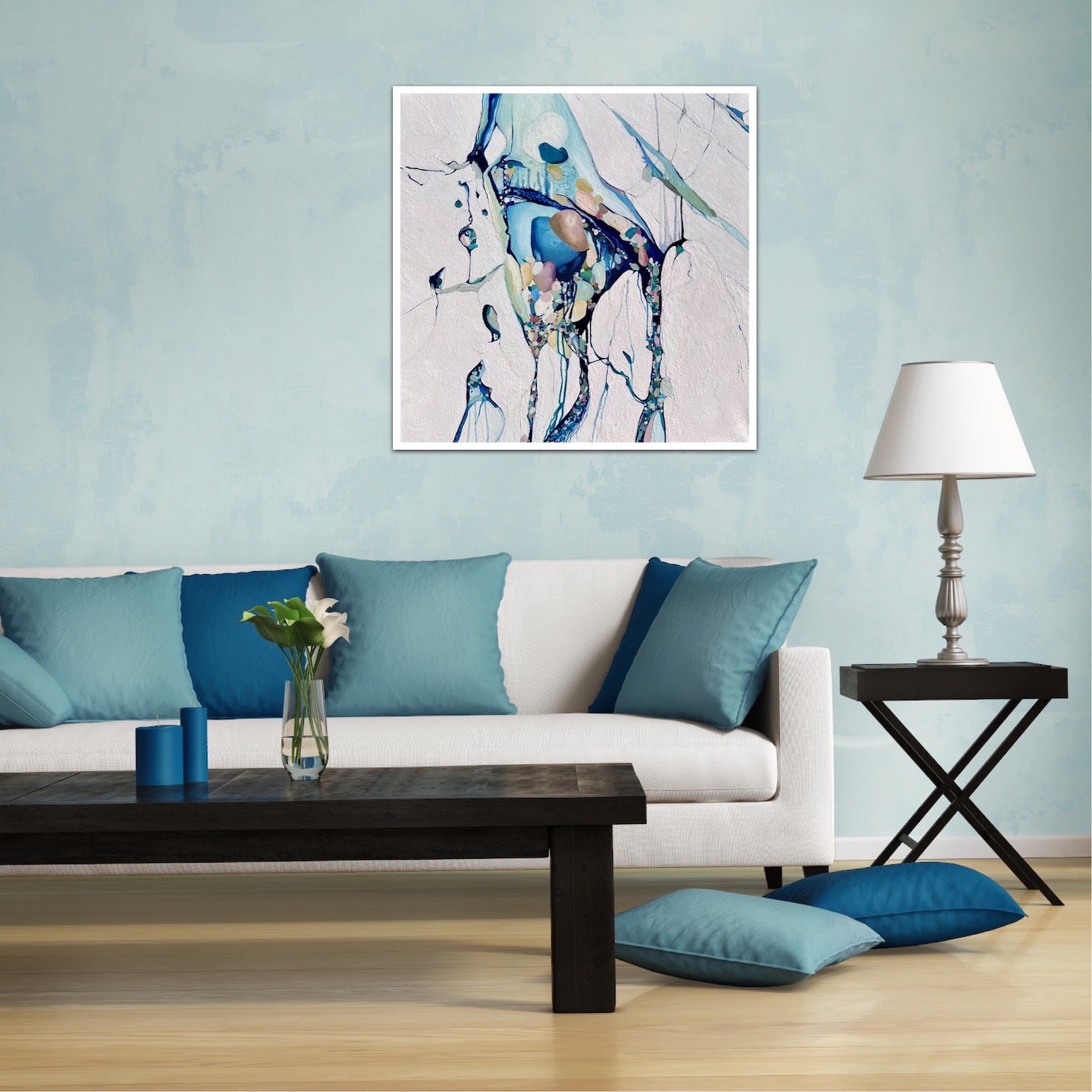 Abstract painting with a background of mostly white with blues and multi coloured detail. Shown on pale blue living room wall.