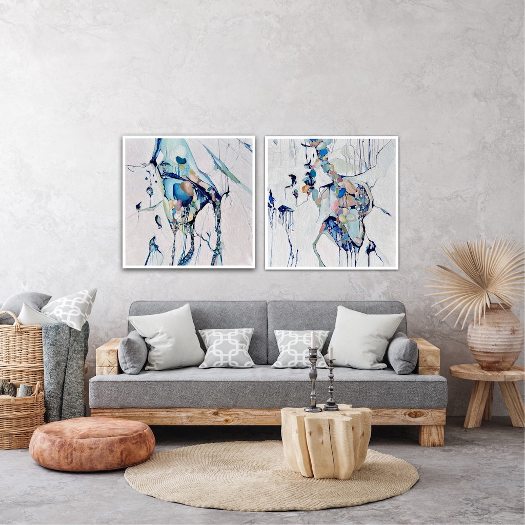 Abstract painting with a background of mostly white with blues and multi coloured detail. Shown above a sofa next to a matching artwork.
