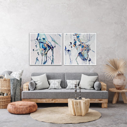 Abstract painting with a background of mostly white with blues and multi coloured detail. Shown above a sofa next to a matching artwork.