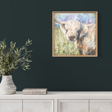 Load image into Gallery viewer, Highland cow with his head turned to the side gazing ahead while standing in a pastel coloured field. In situ on a dark wall.
