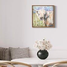 Load image into Gallery viewer, Highland cow with his head turned to the side gazing ahead while standing in a pastel coloured field. In situ on a white dining room wall.
