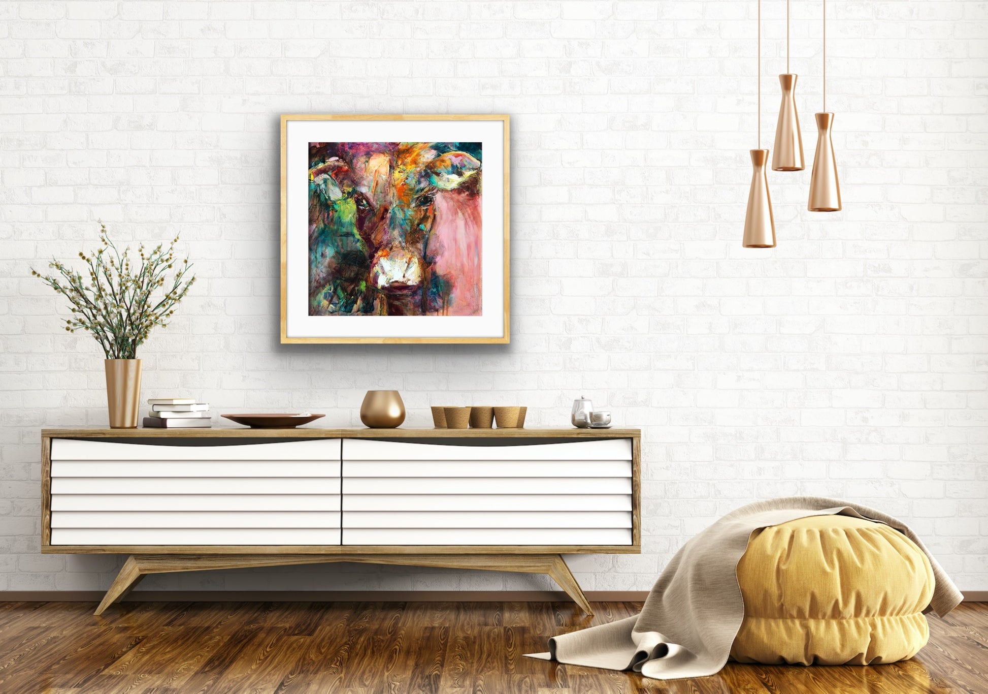 A gorgeous limited edition print of Dairy Queen the cow. Set against a muted, multi coloured background, framed in Tasmanian Oak and shown on a white brick wall.