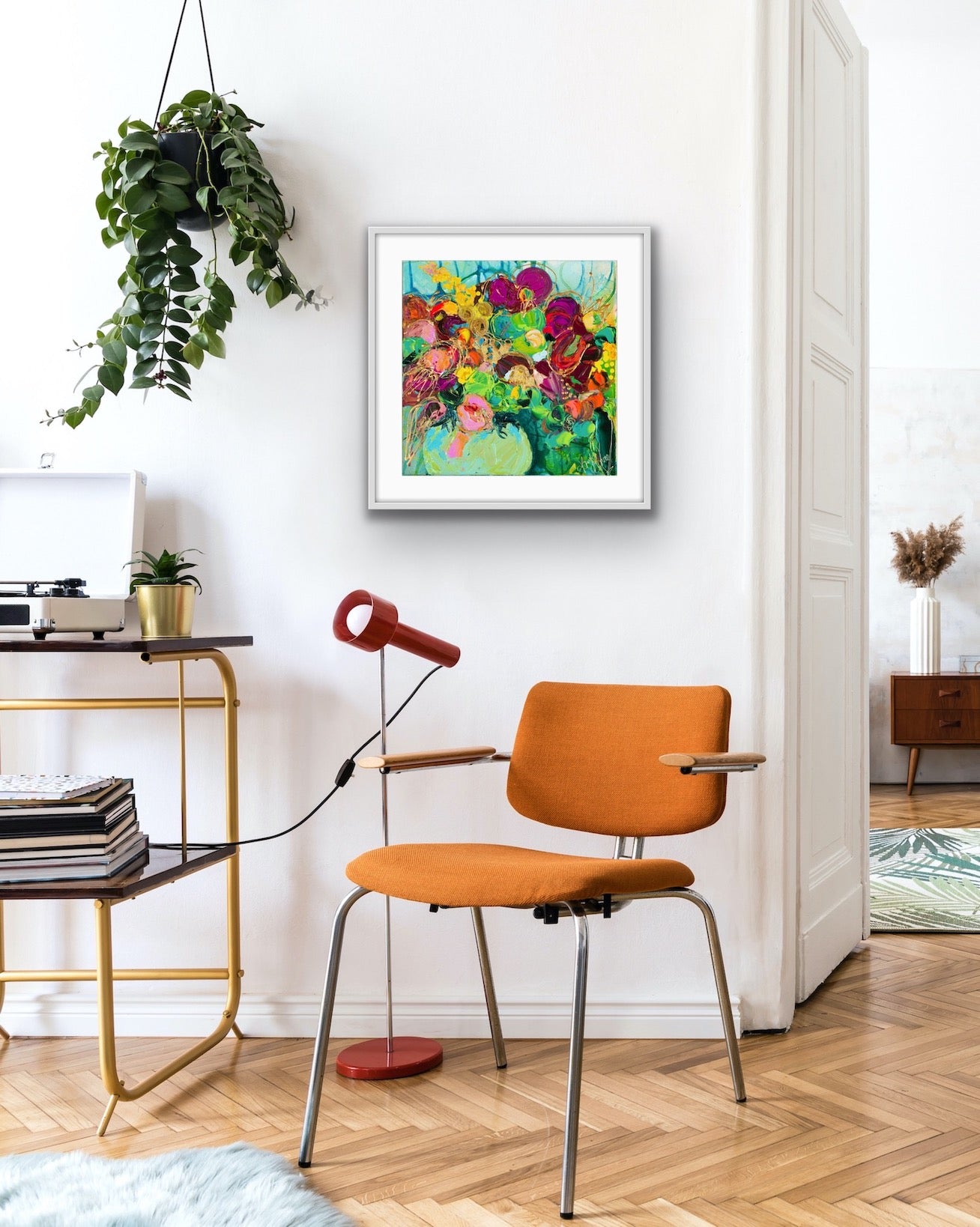 A mass of gorgeous blooms in shades of green, pink, magenta, red and gold in a green glass vase, in a white frame.