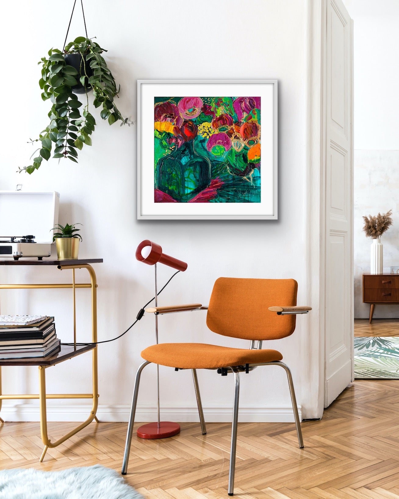 A magnificent bunch of vibrant blooms in a turquoise glass vase against a turquoise, green and magenta background, in a white frame.