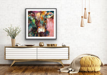 Load image into Gallery viewer, A gorgeous limited edition print of Dairy Queen the cow. Set against a muted, multi coloured background, framed in black, shown against a white wall.
