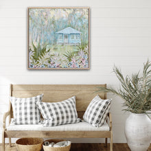 Load image into Gallery viewer, An idyllic pale blue beach cottage with white trim on the windows and verandah. The house is surrounded by palm trees, with a white puppy on the grass in front of the cottage and a garden with fern fronds and flowers. Show in situ on a living room wall.
