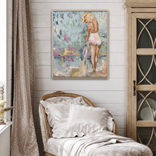 Load image into Gallery viewer, Marilyn Monroe inspired painting showing Marilyn in a contemporary beach setting, holding a towel at the waters edge, against a backdrop of soft tones of aqua, blue, pink, gold. Shown on a white panelled wall above a comfortable chair with cushions.
