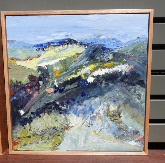 Abstract landscape with flashes of yellow in the countryside and blue mountains and blue sky. Shown in oak frame.