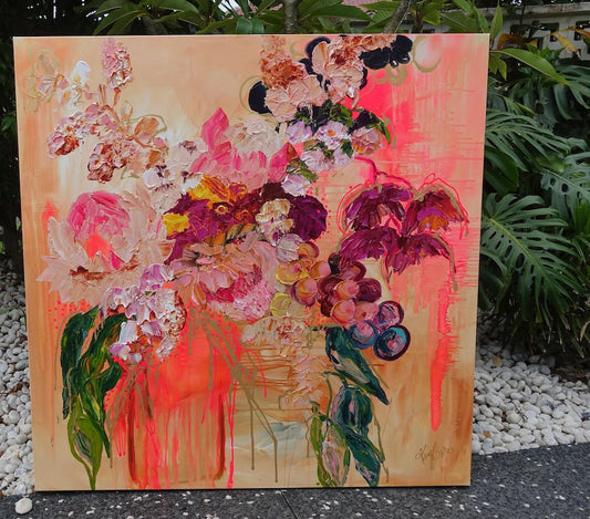 Abundance of blooms in pale pink, hot pink, burgundy and cream with splashes of bright orange on a pale apricot background. Outdoor view.