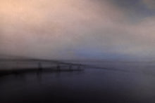 Load image into Gallery viewer, A misty view of a bridge over the ocean with a faint patch of blue showing in the sky.
