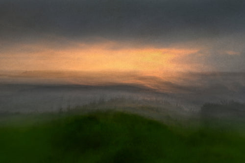 Misty view of a grassy headland looking out to sea, with a touch of yellow and gold in the sky