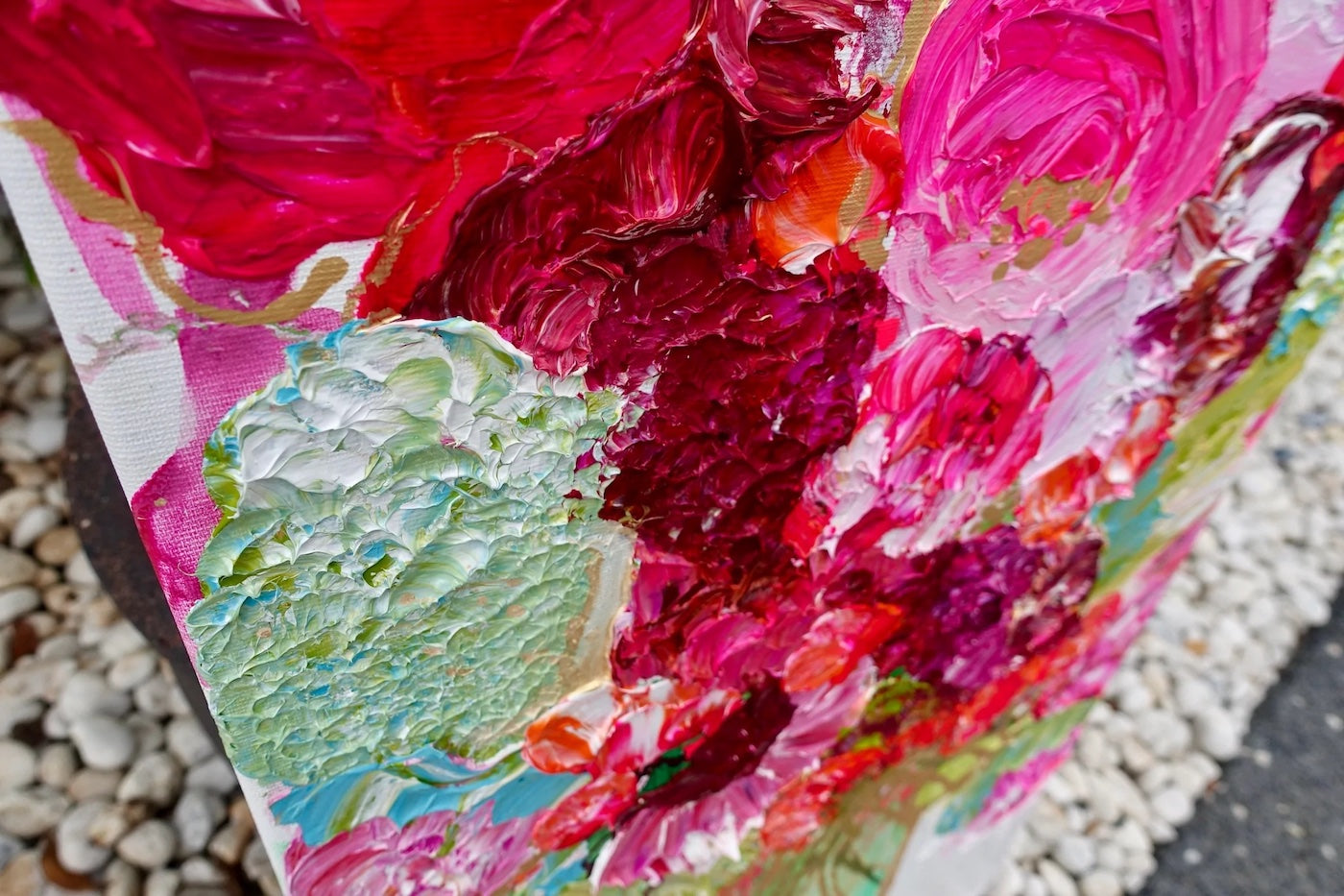 pink, red and pale green blooms in a tall pale green vase. Detail view.