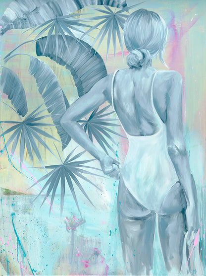 A girl in a white one-piece swimming costume standing on the water's edge, next to tropical trees looking across the water at the sunset.