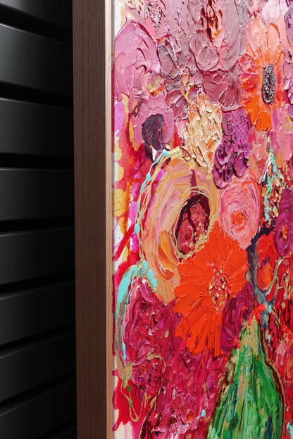 Vibrant colourful mass of blooms in magenta and red, with gold details and a bright green vase. Side view.