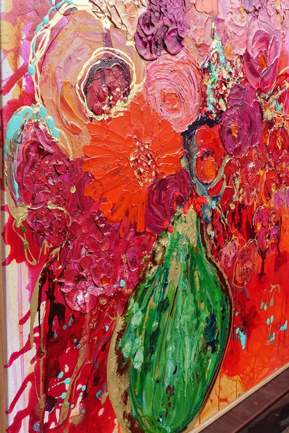 Vibrant colourful mass of blooms in magenta and red, with gold details and a bright green vase. Detail view.