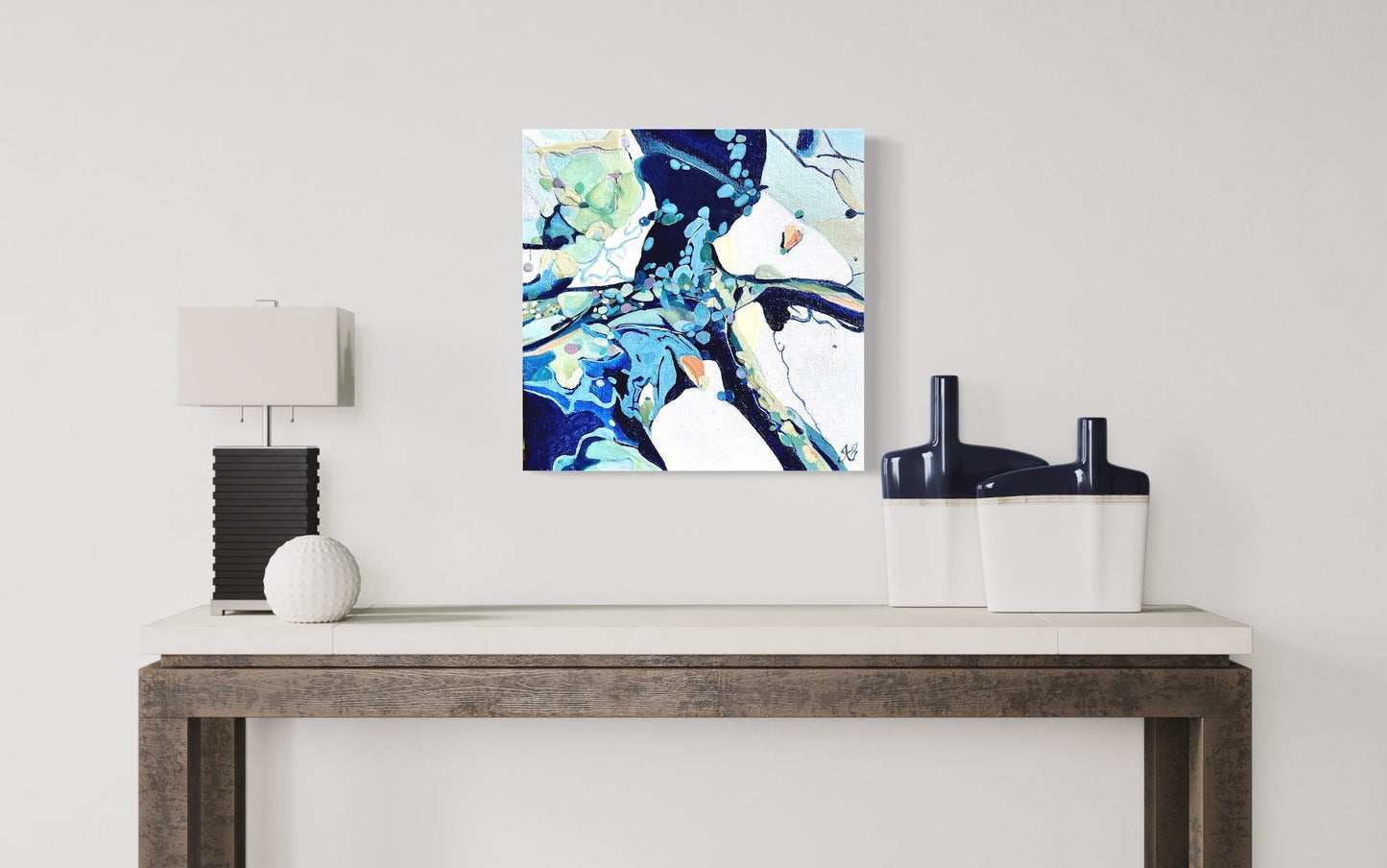 Contemporary abstract painting in shades of blue, aqua, turquoise, green, pink, ochre and white. Shown on a beige wall.