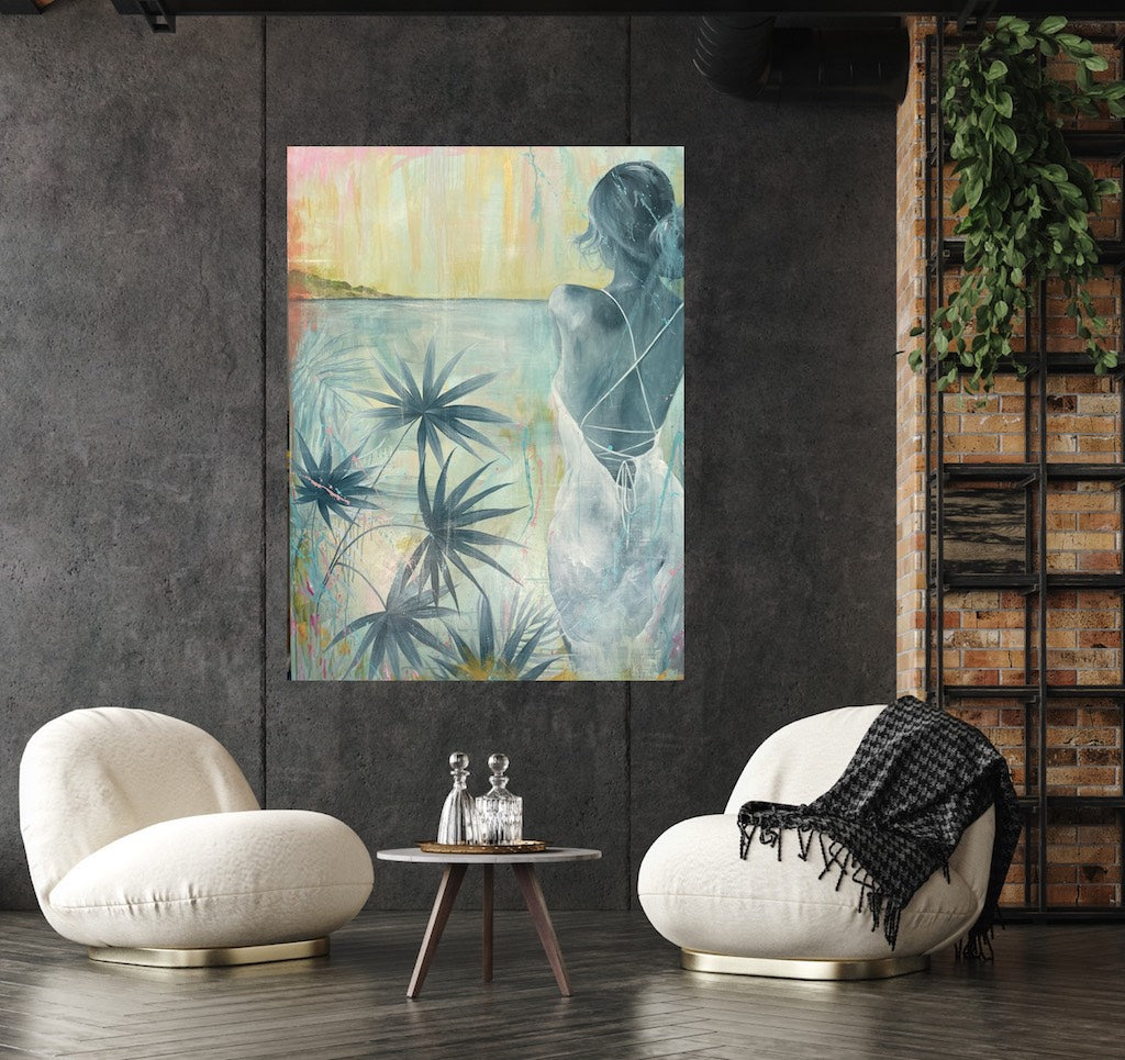 Painting of a girl standing in a white dress gazing across the ocean at dawn. Shown in situ on a dark grey wall in a living room.