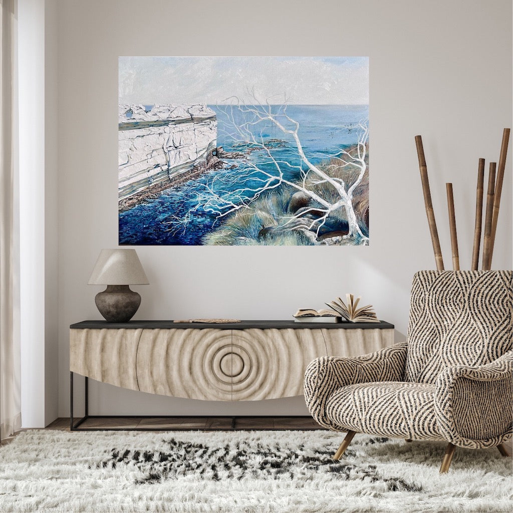 Abstract painting showing a headland jutting out into the ocean, in shades of blue and white. Shown on a beige wall.