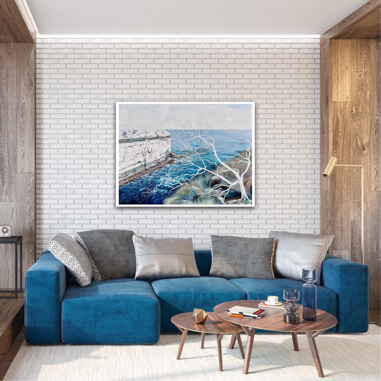 Abstract painting showing a headland jutting out into the ocean, in shades of blue and white. Shown on a brick wall.