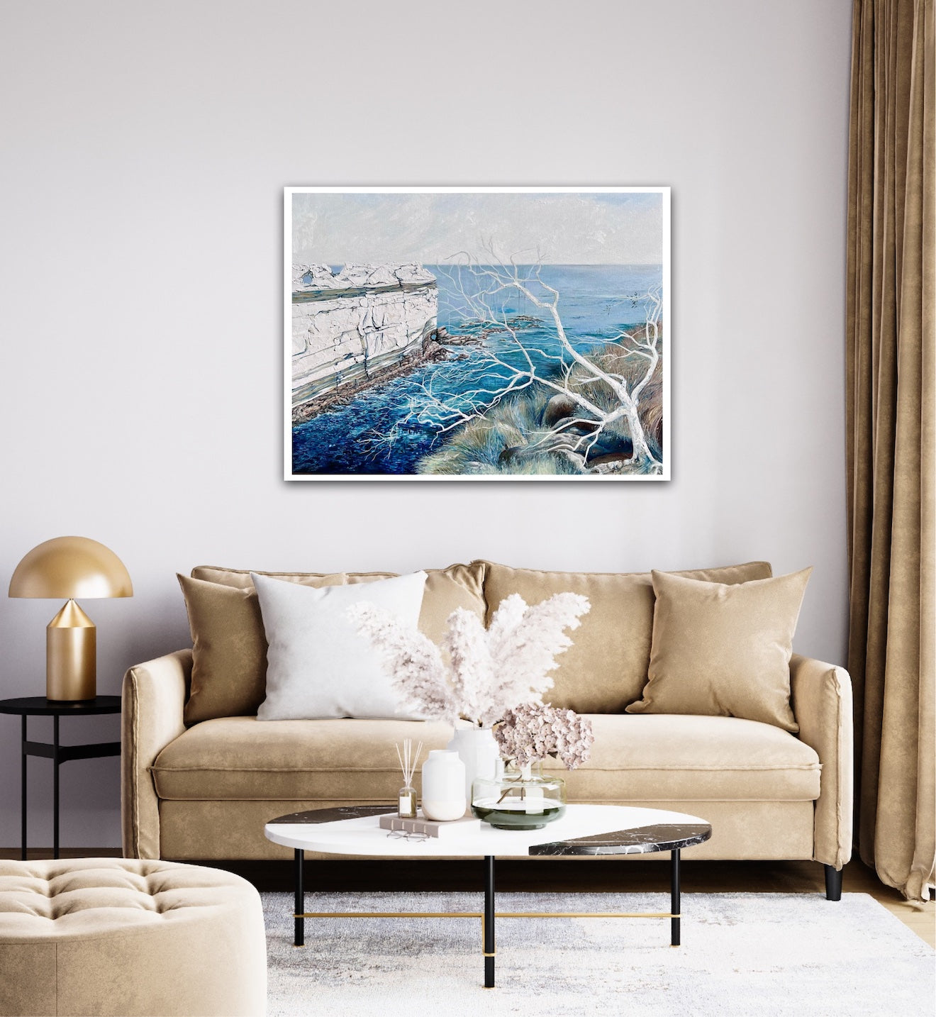 Abstract painting showing a headland jutting out into the ocean, in shades of blue and white. Shown on a living room wall above a sofa.