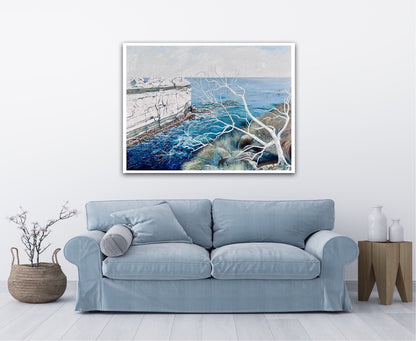 Abstract painting showing a headland jutting out into the ocean, in shades of blue and white. Shown on a white wall above a pale blue sofa.