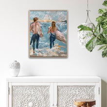 Load image into Gallery viewer, Surf painting with a man and woman standing on the edge of the ocean with surfboards under their arms. Shown on a white wall.
