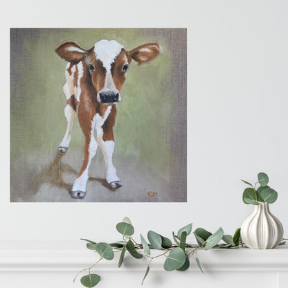Meet Sweetpea, a dear little caramel and white coloured calf standing against a pale green and grey background. Shown in situ on a white wall above a white shelf with a vase and leaf decoration.