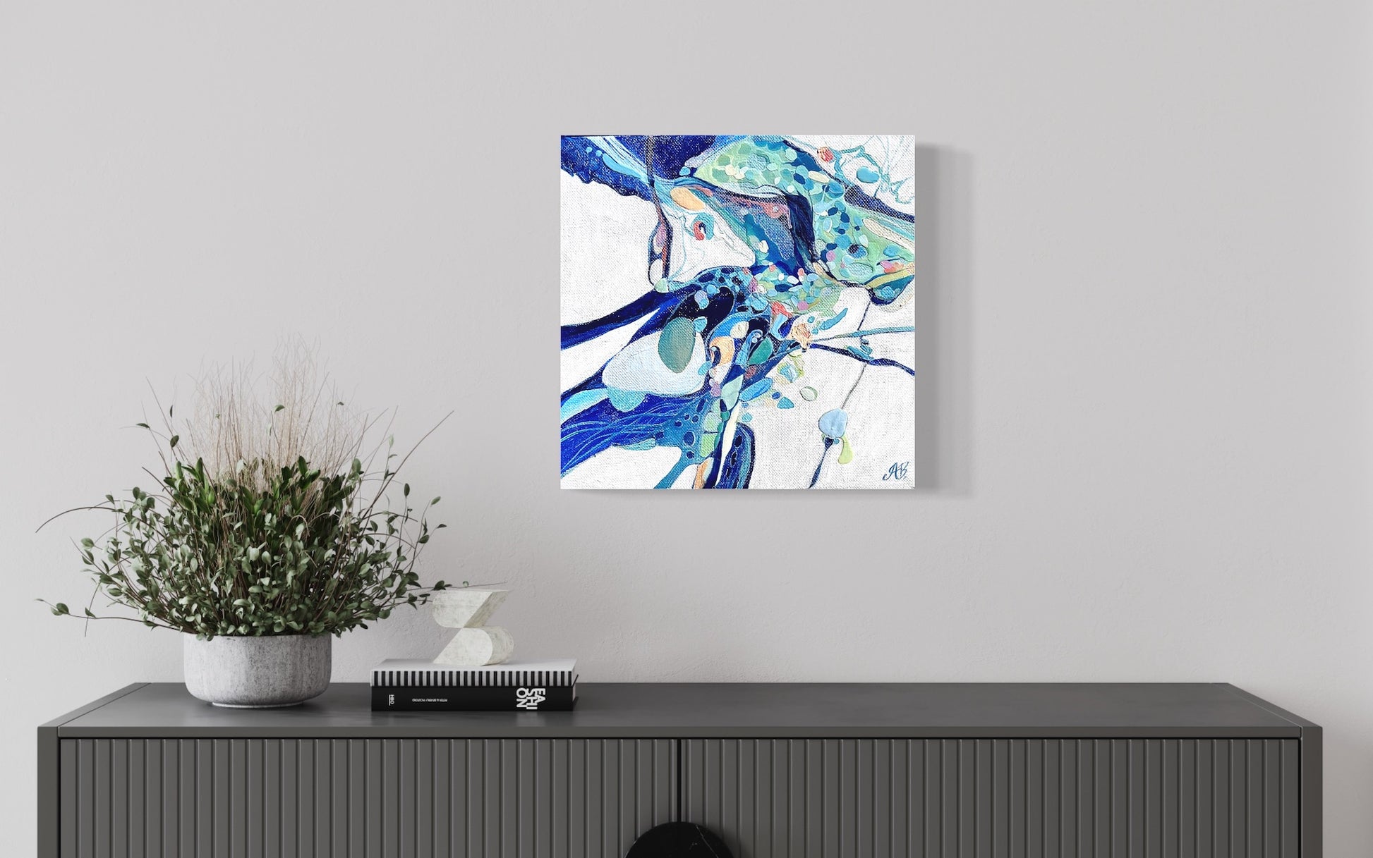Abstract rock pool in shades of blue, aqua, turquoise, rose, mauve, pink ochre and white. Show on a grey wall.