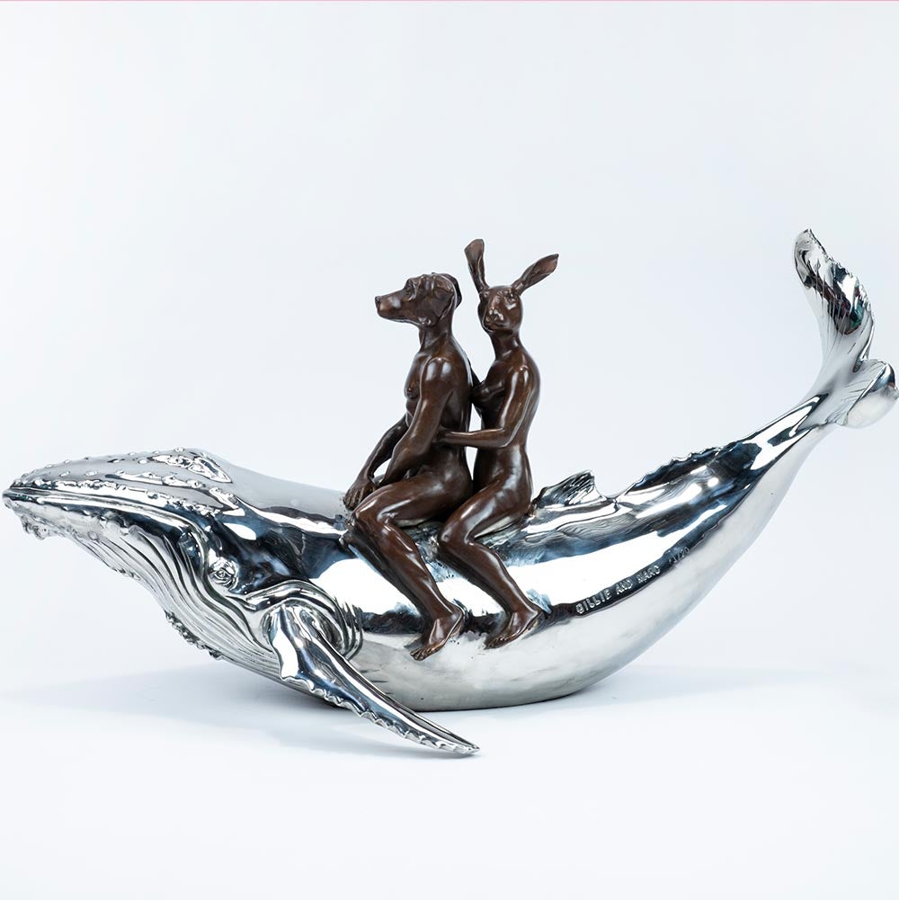 Bronze and stainless steel Sculpture of a dog man and rabbit woman riding on a whale. Side view.